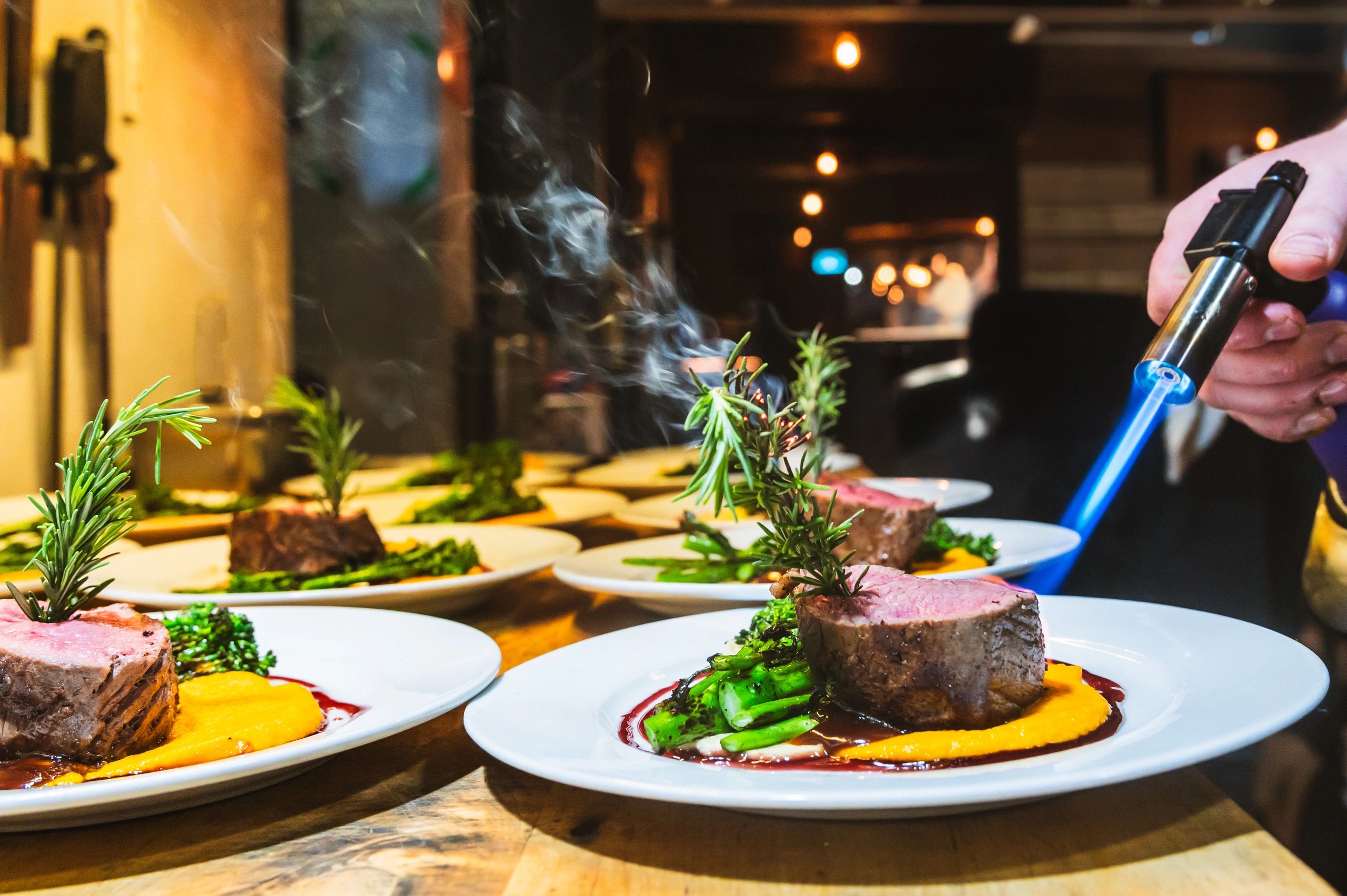 Chef using culinary torch to finish plated fine dining dishes